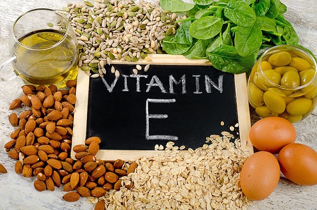 Các loại thực phẩm giàu vitamin E như bó xôi, trứng, yến mạch, hạnh nhân, hạt bí... đang nằm trên bàn