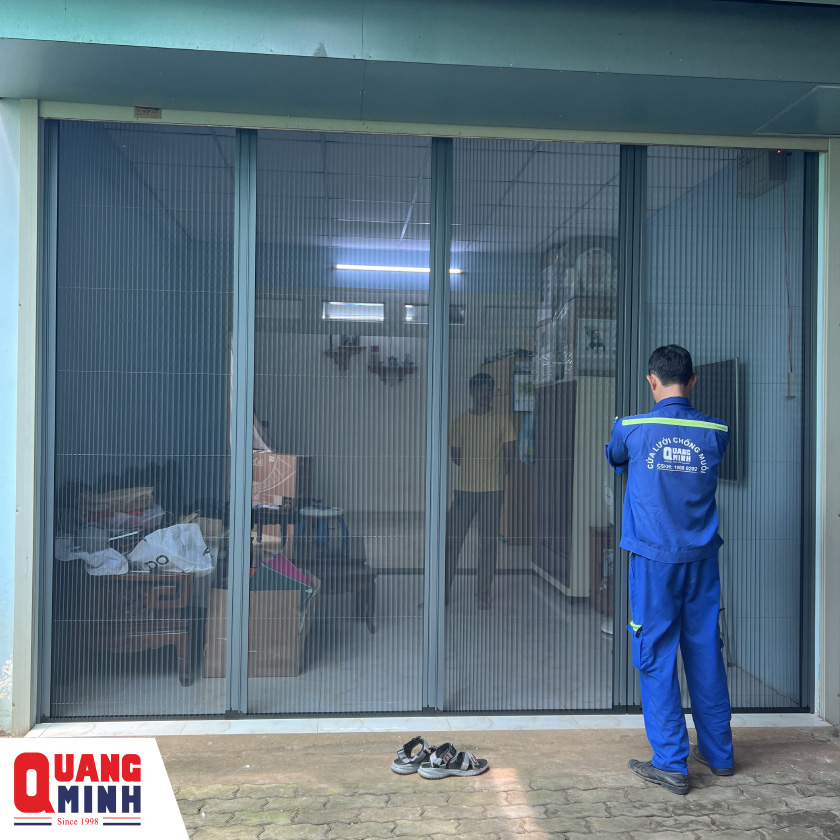 Nhân viên QM đang kéo cửa lưới dạng xếp 4 cánh 
