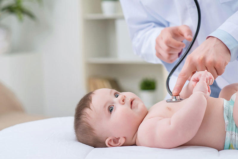 em bé đang được bác sĩ thăm khám bằng ống nghe