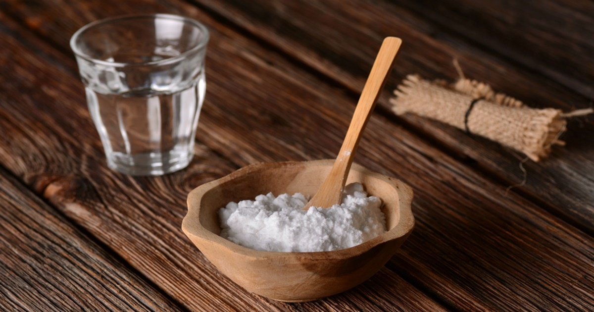 Bột baking soda được chứa trong một cái chén gỗ, trong chén có một muỗng gỗ