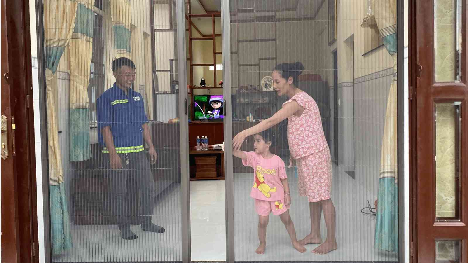 3 người đang mở cửa lưới kéo xếp 2 cánh màu xám