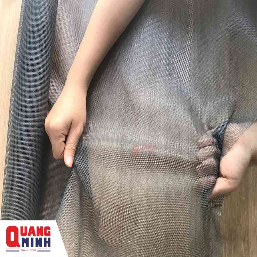 một người đang dùng hai tay kéo giãn tấm lưới màu xám trên nền gỗ