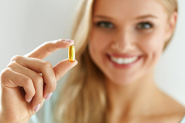 Một cô gái đang cầm vitamin E dạng viên nén