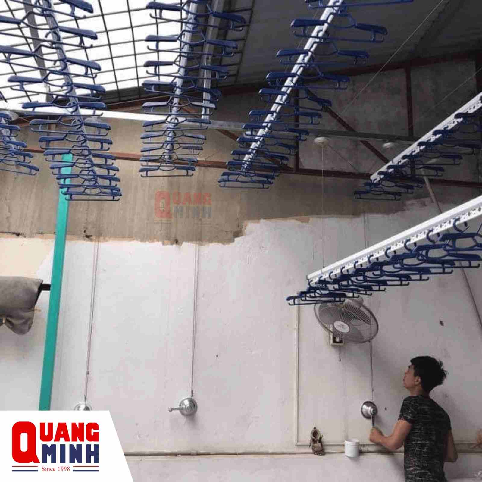 Nhiều giàn phơi treo trần có người đàn ông đang điều khiển kéo lên xuống