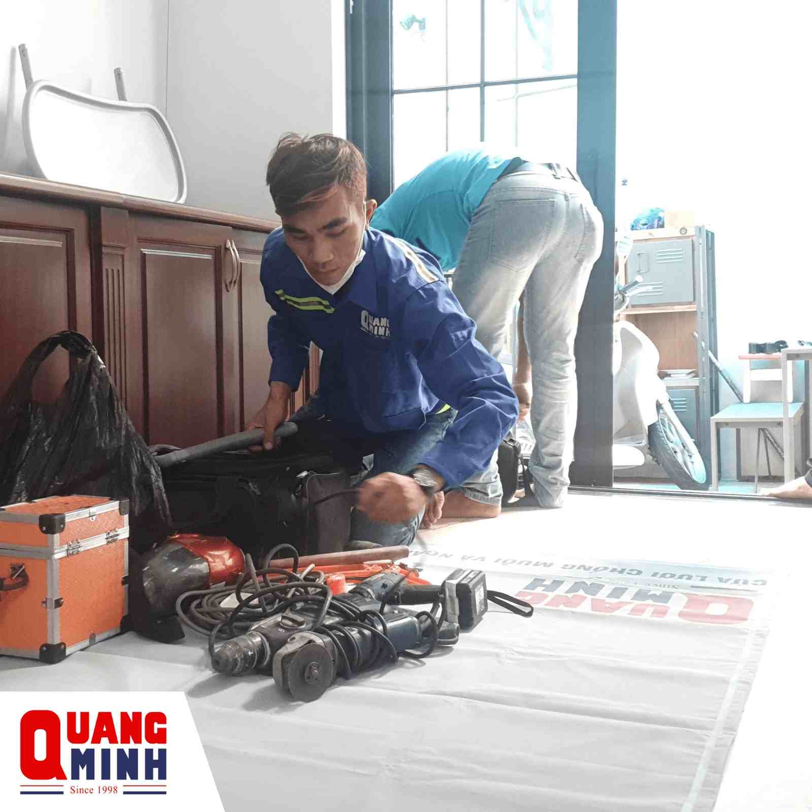 hay nhân viên Quang Minh đang bày dụng cụ lắp đặt cửa