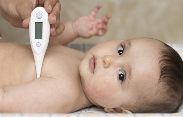 em bé đang nằm ngửa để mẹ đo nhiệt độ ở nách