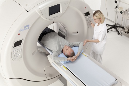 Bác sĩ nữ đang điều chỉnh máy để tiến hành chụp CT cho bệnh nhân nam