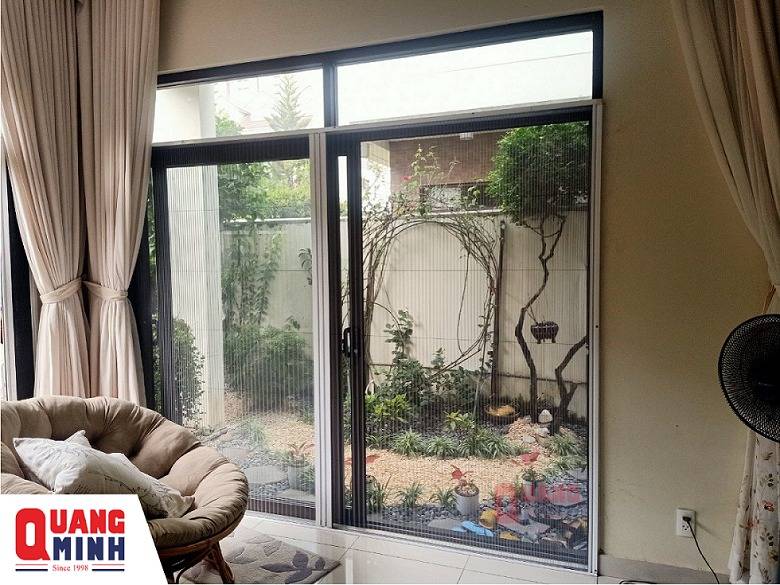 Ảnh cửa lưới chống muỗi kéo xếp được lắp bên hông ngôi nhà, bên ngoài có nhiều cây xanh.